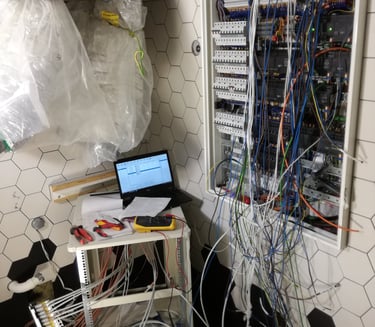 Electrician installing smart home automation wiring and circuit breakers in a wall-mounted panel.