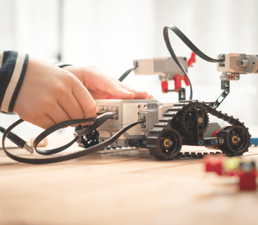 Child building a robotic vehicle with wires and sensors during a STEM activity