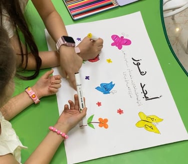 Children decorating an Arabic poster with colorful drawings of butterflies, birds, and flowers