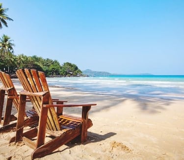 two wooden chairs sitting on a beach
