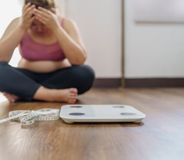woman sitting on the floor with a weight scale