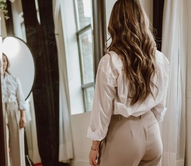 a woman in a white shirt and pants standing in front of a mirror
