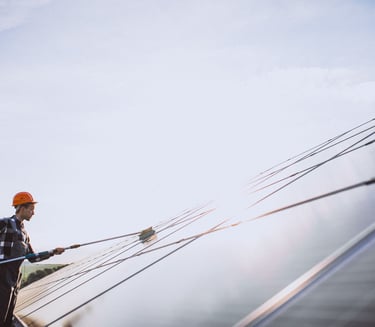 Agent qui nettoie un panneau solaire à la perche