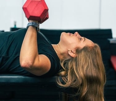 a young lady using dumbbells on a bench