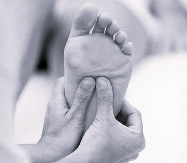 Deux mains massent un pied, réflexologie plantaire