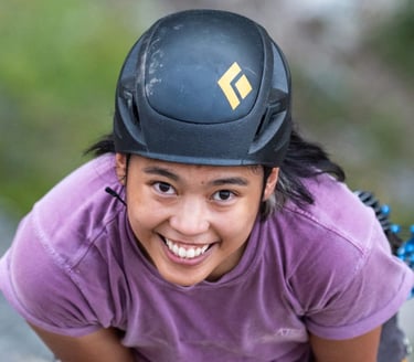 A smiling woman wearing a black helmet and purple shirt