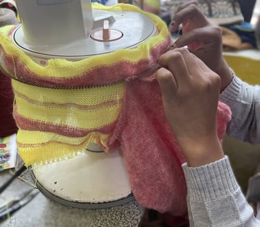 a person is sewinging a sweater with a yellow and red scarf