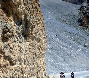 two people riding motorcycles down an alpin mountain side
