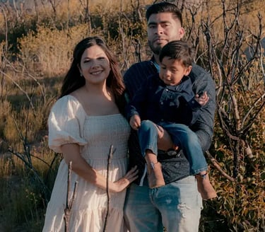 young latin family smiling in a field plain at sunset with a young toddler