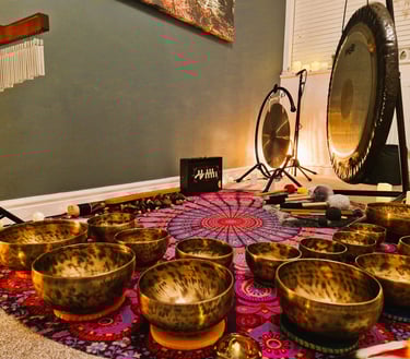 Shruti box, chimes, gongs, and many singing bowls arranged on a mat