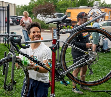 Smiling young man washing a bike with a sponge