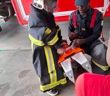 A professional firefighter helps a child from the creative workshop put on a firefighter uniform to 