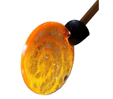 A golden yellow resin disc with lace-paper embedded in it.