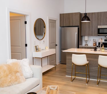 Modern open concept kitchen and living room featuring wood cabinets, quartz island, and gold accents.