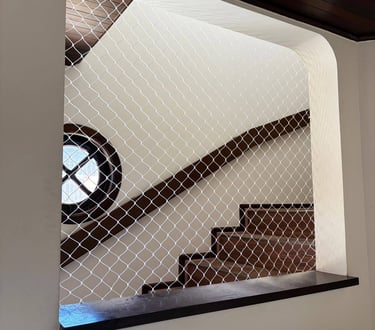 Rede de proteção fixada em nicho interno, vista para lance de escadas.