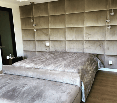 Upholstered bed with velvet wall panels in a modern bedroom by Solo Home Decor.
