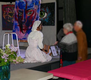 Artiste en interaction avec le public sur scène lors d'une exposition, entourée de grandes peintures