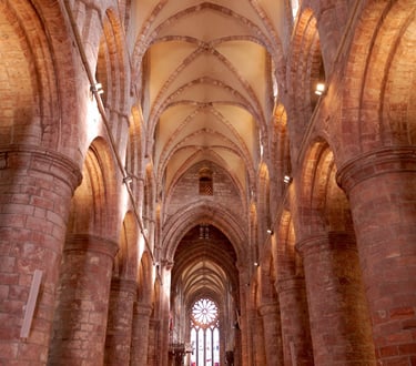 a church with a large stone vaulted ceiling and a church pew area