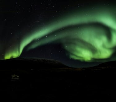The green ribbon of Northern Lights in the night sky