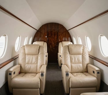 Wide interior shot of a private jet cabin looking toward the cockpit, cream leather seats and polished wood veneer panels, soft natural light flooding through oval windows, no passengers, clean and still