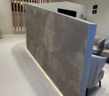Modern dental surgery waiting room with grey chairs and a decorative microcement concrete wall with
