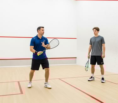Squash coach and a client playing squash on a court