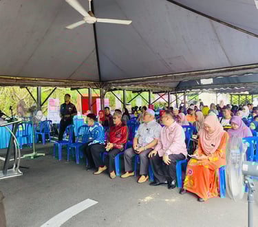 Community members gather under a tent for an outdoor seminar with a guest speaker at a local event.