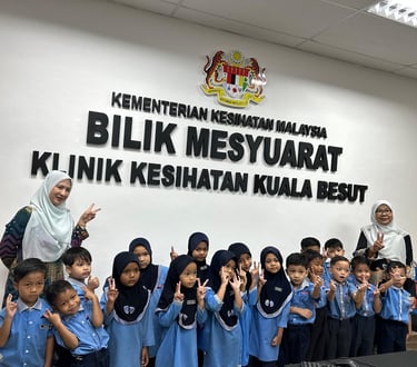 Malaysian preschool children visit Kuala Besut Health Clinic meeting room with teachers for educational tour.