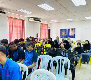 Students in blue shirts and hijabs attending an educational seminar in a bright classroom.