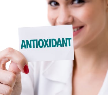 A smiling healthcare professional holding a card with the word ANTIOXIDANT in green text.