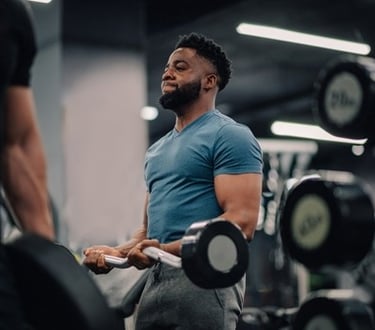 A man performing bicep curls with a barbell during a strength training workout in a modern gym.