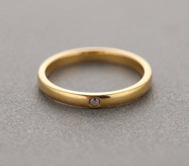 Stack of finely crafted rings with mixed metals and subtle gemstone accents arranged on a wooden tray.