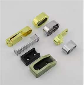 Collection of polished gold, silver, and black metal furniture hardware components on a white background.