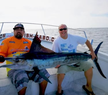 two men are holding a fish on a boat