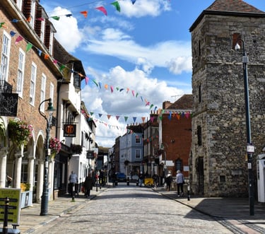 Rue pavée ensoleillée avec des batiments en briques rouges et des drapeaux colorés