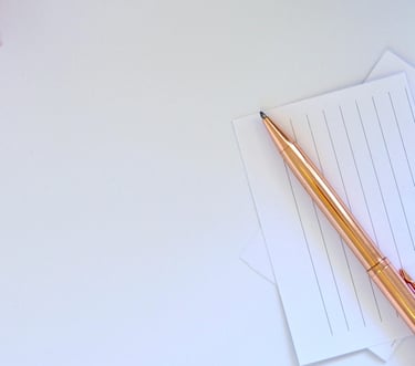 Close-up of a golden pen placed on lined paper.