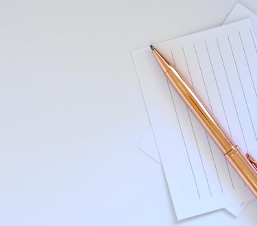 Nahaufnahme eines goldfarbenen Stifts auf liniertem Papier.