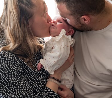 des parents faisant un bisou à leur bébé