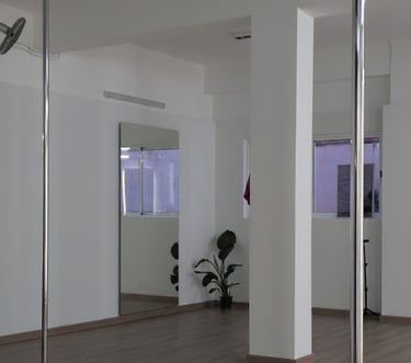 Un estudio de baile o ejercicio con dos postes verticales de metal en primer plano. El techo es negr