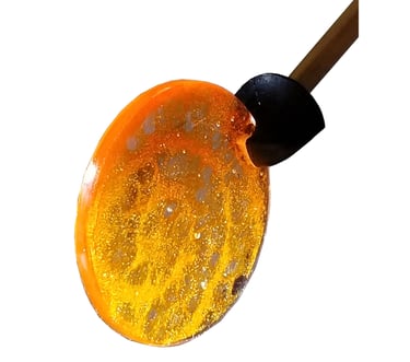 A golden yellow resin disc with lace-paper embedded in it.