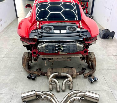 Red Porsche 911 at an auto repair shop for a high-performance exhaust system upgrade.