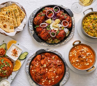 Indian feast with tandoori chicken, butter chicken curry, basmati rice, and garlic naan bread.