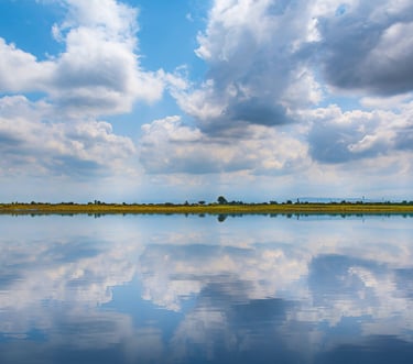 A horizon of the sky and river meeting with a thin layer of earth in between