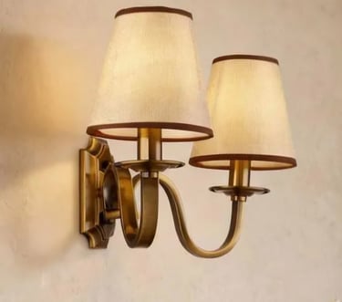 Antique brass double wall sconce fixture with two bell-shaped fabric lamp shades.