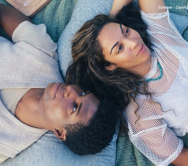 a man and woman laying on a blanket