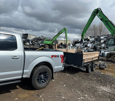 Truck and trailer being unloaded by a crane with a magnet at the metal recycling center