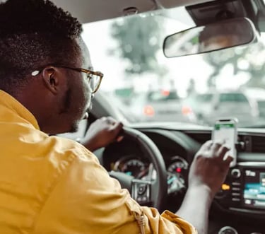 A rideshare driver using a smartphone GPS navigation app while driving a car in city traffic.