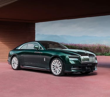 Rolls-Royce Spectre luxury electric coupe in deep green, parked in a scenic modern setting.