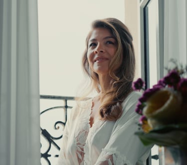 Mariée en robe de chambre en dentelle regardant par la fenêtre le jour de son mariage