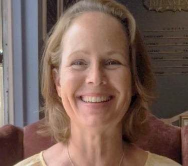 a woman in a yellow dress smiling and holding a cake